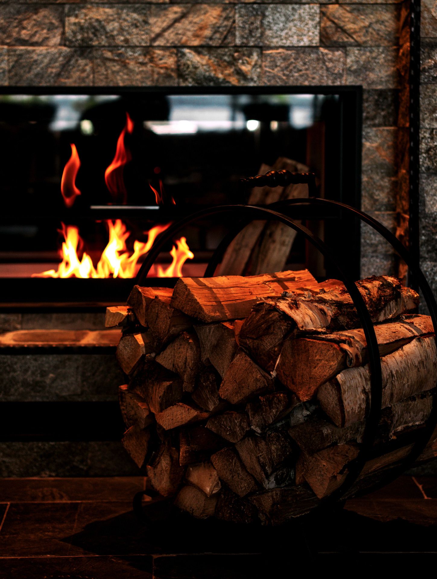 Stone fireplace with fire, reflective glass and logs